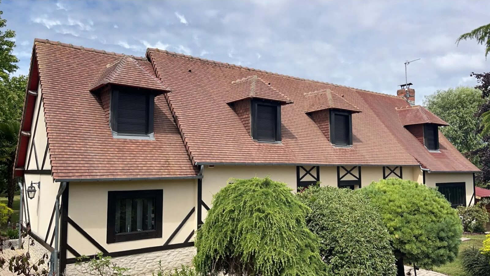 Lucarnes à croupe en tuile plate sur une maison à colombages du Pays d'Auge