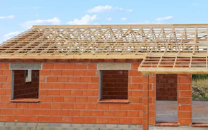 Charpente fermette : fermes industrielles triangulées posées sur une maison en cours de construction